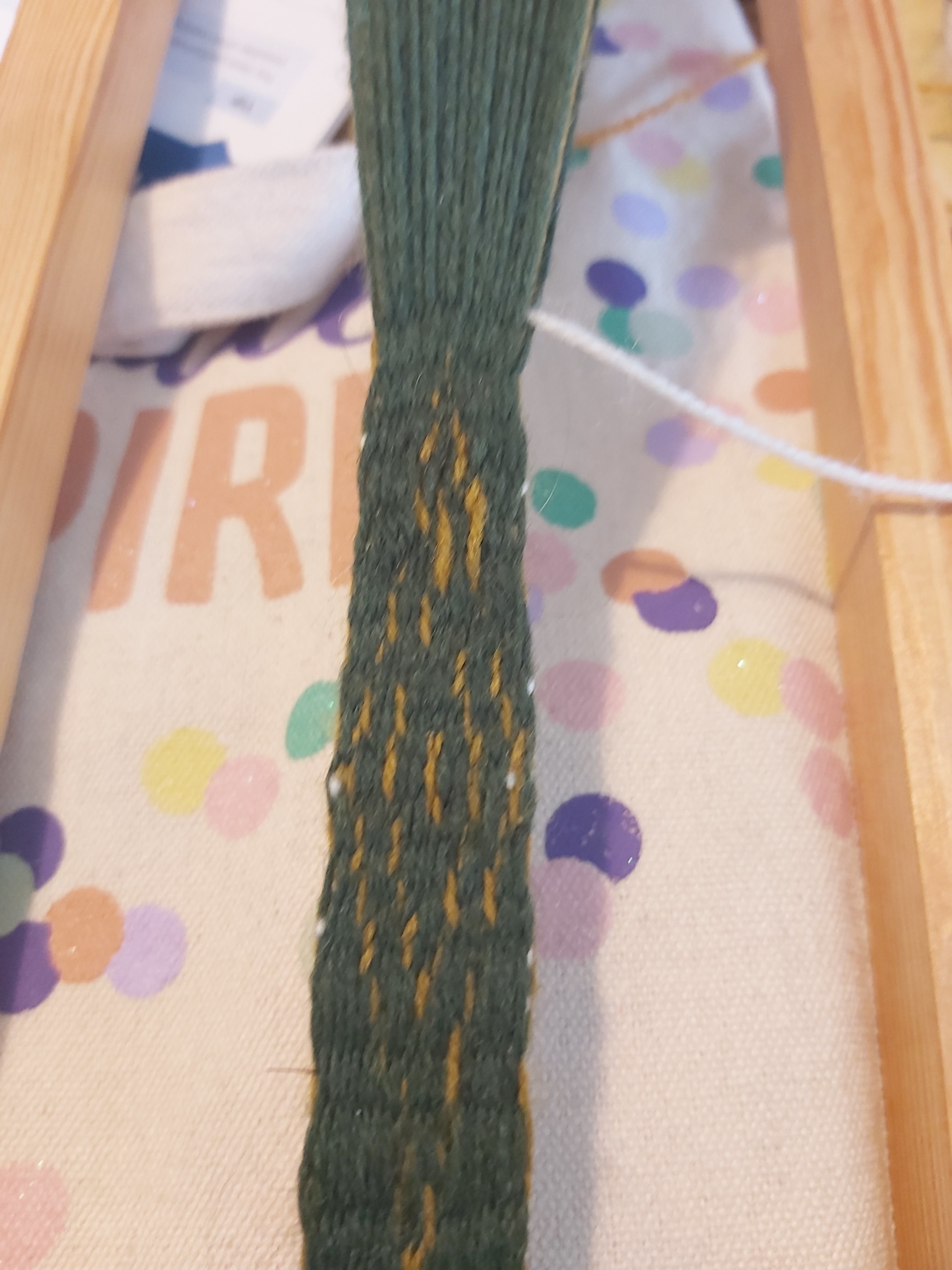 Sir Gawain Pt 2 Figure 6 A strip of dark green woven cloth with a lighter green lozenge woven into it. Part of the lozenge is misshapen