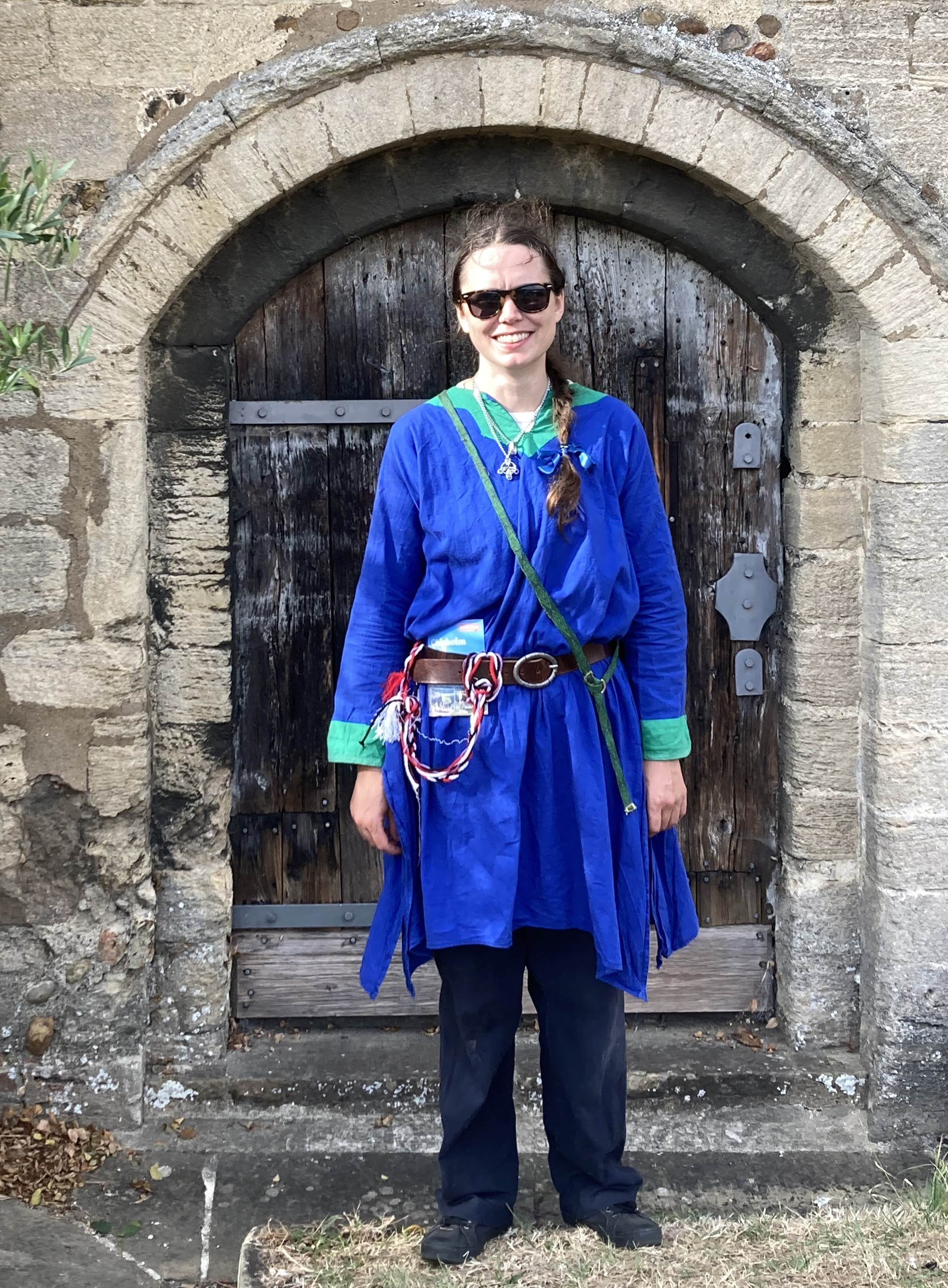 A person in medieval costume, wearing a strip of tablet-weaving as a sash